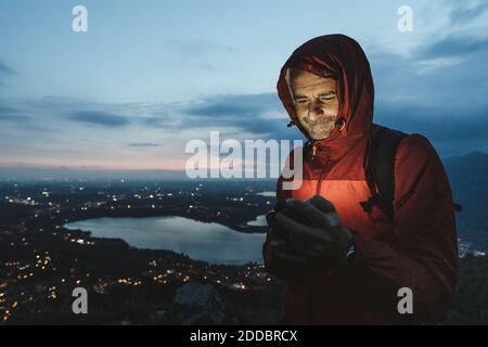 Mature male hiker using mobile phone against sky at twilight Stock Photo