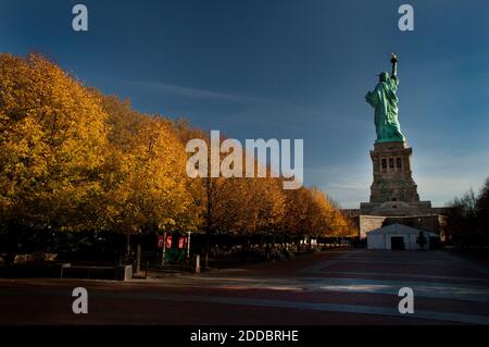 Statue of Liberty in the early morning light during the Fall season.  Yellow and orange leaves on the trees in Liberty State Park. Stock Photo