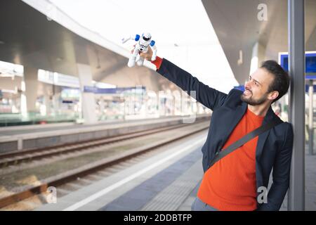 Smiling entrepreneur looking at robot on railroad platform Stock Photo