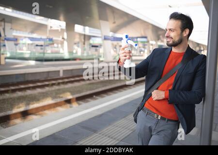 Smiling entrepreneur looking at robot while standing on railroad platform Stock Photo