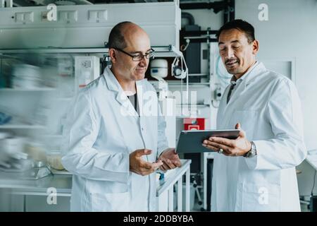 Scientist using digital tablet while standing at laboratory Stock Photo