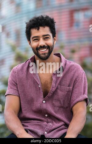 Happy man wearing pink shirt while sitting in city Stock Photo