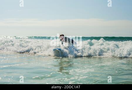 Teenage boy surfing in sea against sky at beach Stock Photo