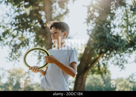 Boy throwing frisbee ring while standing in public park Stock Photo