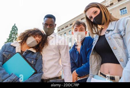 University students wearing protective mask while standing against education building Stock Photo