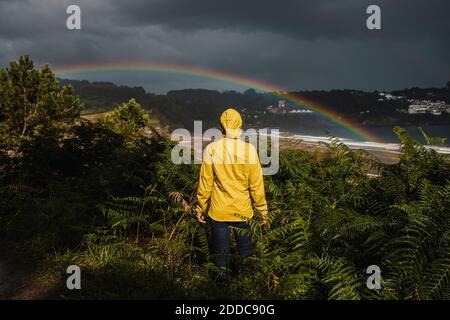 Rear view of woman wearing raincoat during rainy season Stock Photo