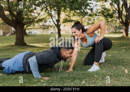 Smiling woman looking at man doing push up at backyard Stock Photo
