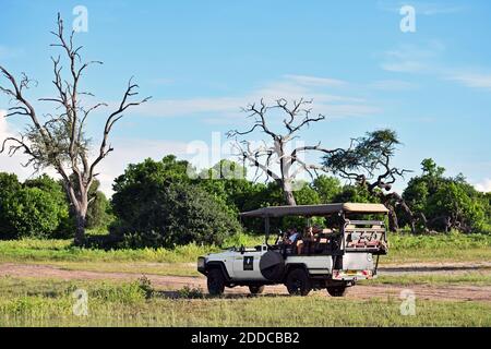 A game drive vehicle with tourists on a safari stop for a break to watch wildlife along a dirt road in Chobe National Park, Botswana, Africa Stock Photo