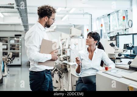 Confident female technician discussing with male colleague at laboratory Stock Photo
