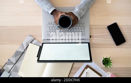 Hands of businesswoman holding coffee cup while using at home Stock Photo
