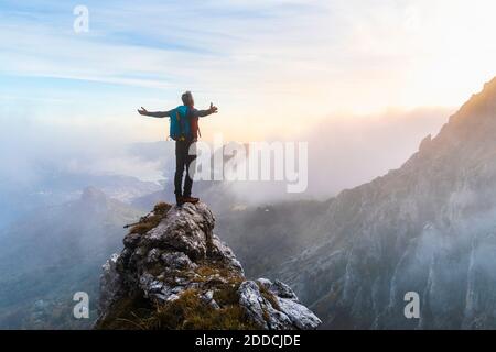 Pensive hiker using smart phone on mountain peak during sunrise at  Bergamasque Alps, Italy stock photo