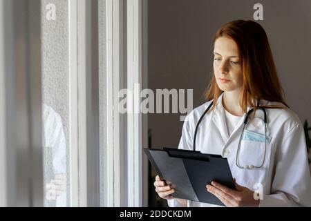 Young female doctor examining medical record at home office Stock Photo
