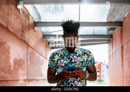 Close-up of African man using smart phone while standing amidst walls Stock Photo