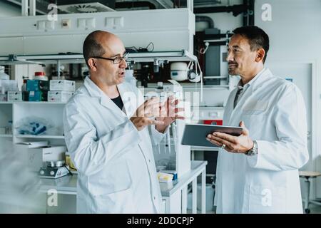 Scientists discussing while using digital tablet at laboratory Stock Photo