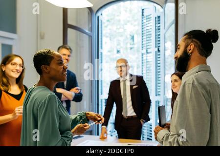 Smiling male and female business professionals discussing at workplace Stock Photo