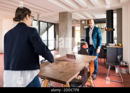 Man and woman playing while standing by table at cafeteria in office Stock Photo