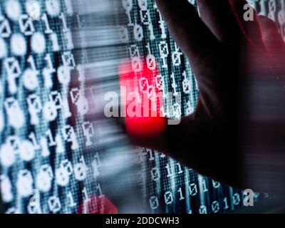 Close-up of hand touching computer screen with binary code Stock Photo