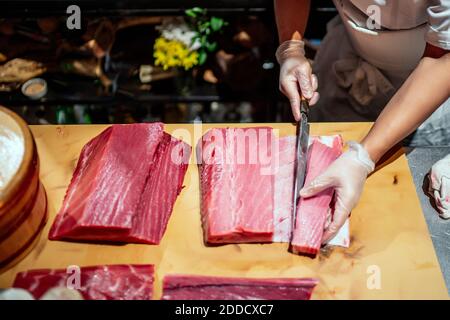 Chef cutting large fish at counter in kitchen of restaurant Stock Photo