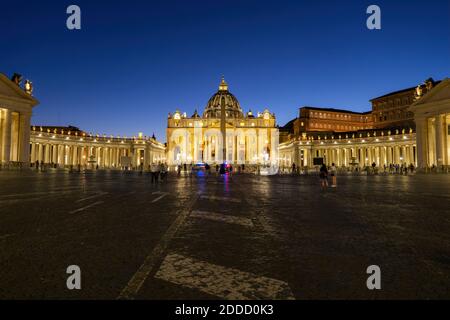 Tourists at illuminated St. Peter's Square with St. Peter's Basilica against clear blue sky at night, Vatican City, Rome, Italy