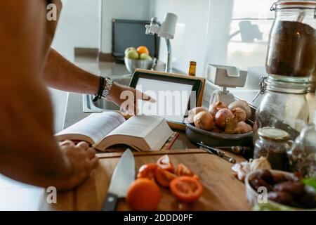Cropped image of human hand using digital tablet in kitchen Stock Photo