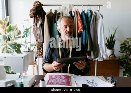 Mature tailor using digital tablet while working at studio Stock Photo