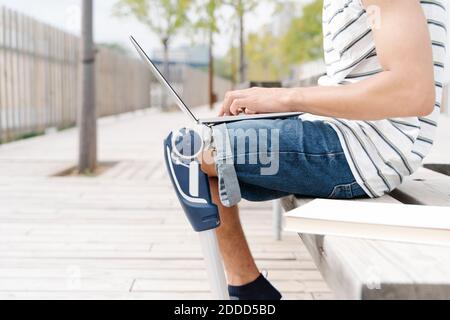 Midsection of man with artificial limb using laptop in city Stock Photo