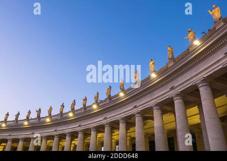 Illuminated saint statues on St. Peter's Basilica against clear blue sky at dusk, Vatican City, Rome, Italy Stock Photo