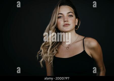 Attractive young woman standing against black wall Stock Photo