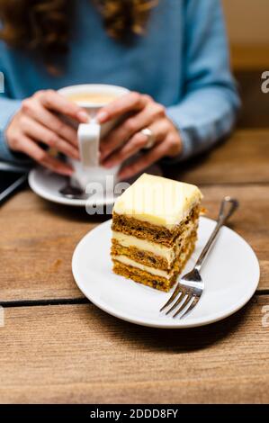 Woman with coffee and carrot cake on table Stock Photo
