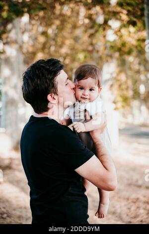 Man kissing baby boy while standing outdoors Stock Photo