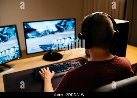 Young man playing video games with computer at desk Stock Photo