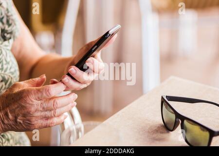 Senior woman using mobile phone while sitting by table at cafe Stock Photo