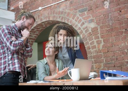 Employees discussing while working together at office Stock Photo