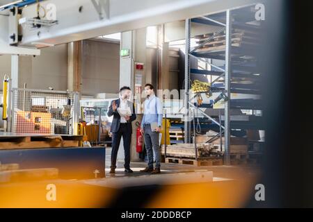 Young and mature businessmen having discussion while standing at factory Stock Photo