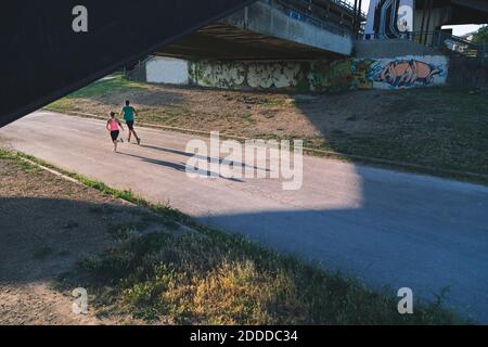Fit young couple jogging under bridge on street Stock Photo