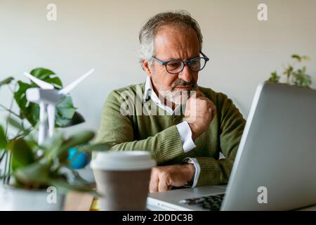 Man wearing eyeglasses using laptop while sitting by table at home Stock Photo