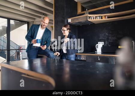 Business people using mobile phone while drinking coffee at office Stock Photo