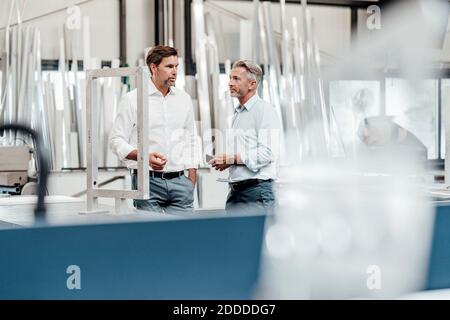 Businessmen discussing while standing in factory Stock Photo