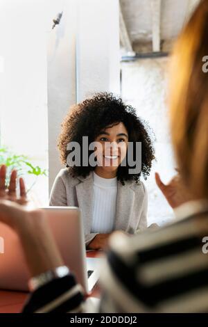 Smiling coworkers discussing while sitting in cafe Stock Photo