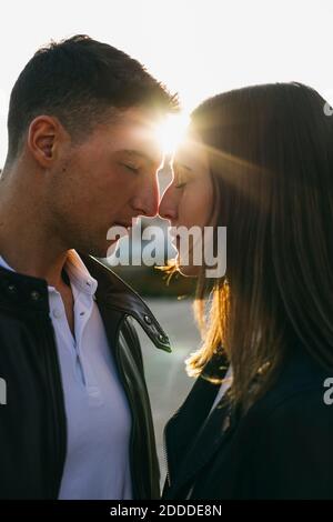 Young couple standing face to face with eyes closed during sunset Stock Photo