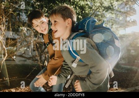 Smiling brothers running in public park on sunny day Stock Photo