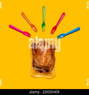 Vacuum packed roasted chicken with multi colored forks on yellow background Stock Photo