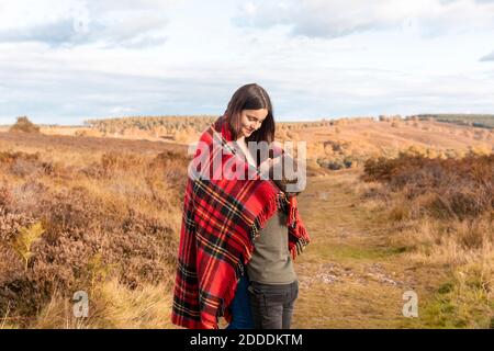 Brother and sister embracing each other while standing in park during autumn Stock Photo