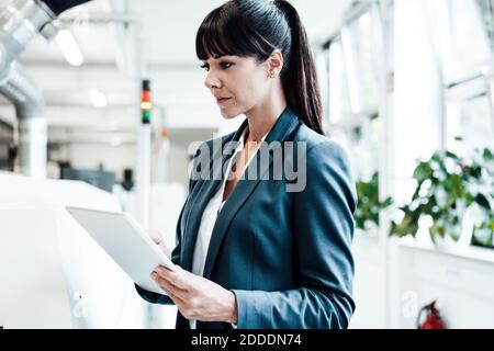 Confident businesswoman using digital tablet at industry Stock Photo