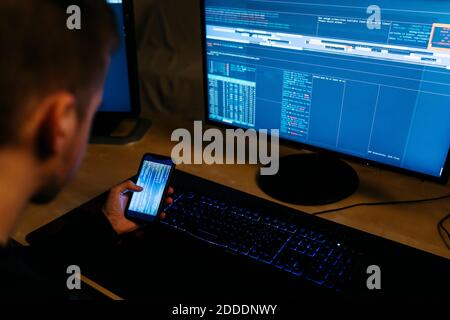 Male computer hacker using mobile phone while working at office Stock Photo