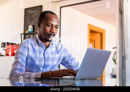 Serious businessman using laptop at table in coworking office Stock Photo