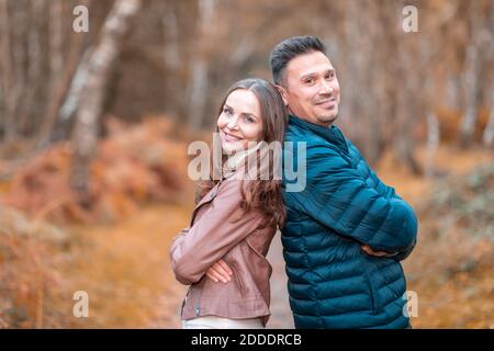 Couple standing back to back with arms crossed in park during autumn Stock Photo
