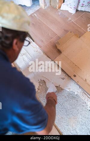 Male manual worker laying cement on parquet floor in house Stock Photo