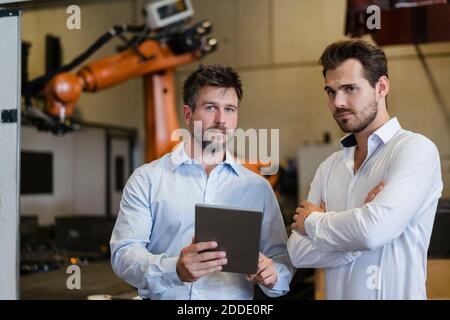 Confident businessmen using digital tablet while standing at factory Stock Photo