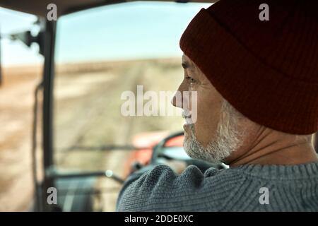 Farmer harvesting crops with tractor at soybean farm Stock Photo